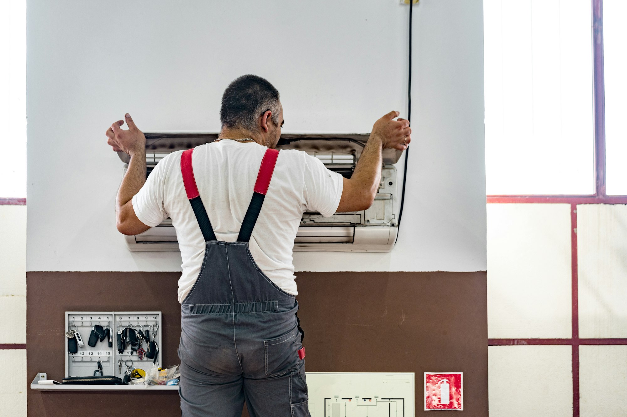 Repairman checking and repairing air conditioner indoors